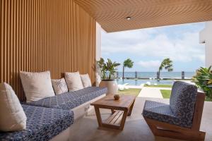 a living room with a couch and chairs and the ocean at Bohemian Beachfront Apartments in Pabean Buleleng