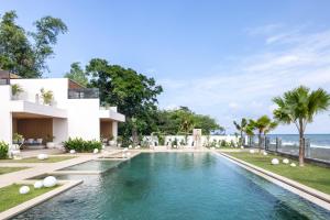 an image of a swimming pool in front of a house at Bohemian Beachfront Apartments in Pabean Buleleng