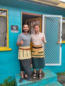 two men standing in front of a blue house at Buddle Camping Ground in Nuku‘alofa
