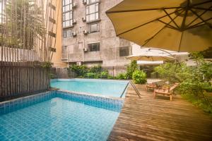 a swimming pool with an umbrella next to a building at Morning Sun Hotel in Yangshuo