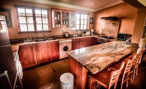 a kitchen with a marble counter top and wooden cabinets at The FarSide Dam Cottage in Nottingham Road +19 photos