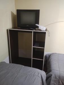 a tv sitting on a stand next to a bed at Hostal Claunorte in Calama