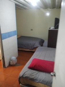a bedroom with two beds and a red pillow at Hostal Claunorte in Calama