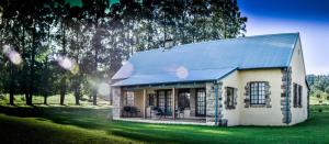 a small white house with a blue roof at The FarSide Dam Cottage in Nottingham Road