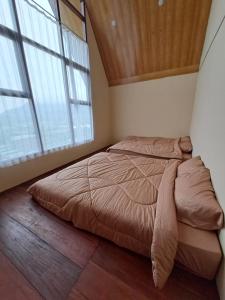 a bedroom with a large bed in a room with windows at Carika Cabin in Diyeng