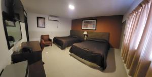a hotel room with two beds and a chair at hotel villa del sol chihuahua in Chihuahua