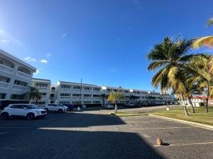 a parking lot with palm trees in front of a building at Verano Azul Beachfront Apartment in Isabela in Isabela
