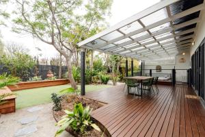 a patio with a wooden deck with a table at The Greenhouse - Spa & Fire - Pet Friendly in Barwon Heads