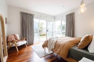 a bedroom with a bed and a chair and windows at The Greenhouse - Spa & Fire - Pet Friendly in Barwon Heads