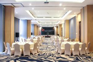 a conference room with white tables and chairs and a screen at Swiss-Belhotel Sorong in Sorong
