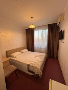 a small bedroom with a bed and a window at TERRA Hotel in Almaty