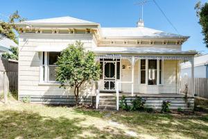 a white house with a porch and a door at Perfect Point Lonsdale Cottage in Point Lonsdale