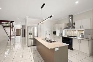 a large kitchen with a sink and a refrigerator at Roderick Street 83, Moffat Beach in Caloundra