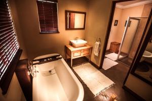 a bathroom with a bath tub and a sink at The FarSide Dam Cottage in Nottingham Road