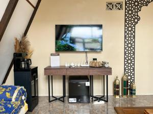 a table in a room with a tv on the wall at The Phalosaa Villa unit Cabana in Ngaglik