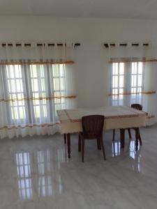 a dining room with a table and chairs and windows at Ocean whisper residence in Ahangama