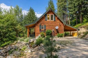 a log cabin in the woods with a driveway at Raven Haven Lodge by NW Comfy Cabins in Leavenworth