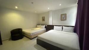 a hotel room with two beds and a chair at Hotel Vistana Micassa in Taiping