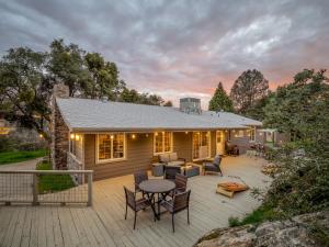 a house with a deck with a table and chairs at Manzanita Hill-35 miles to Yosemite, 10 miles to Mariposa with 8 person spa in Mariposa