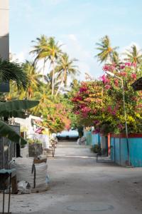 a street with flowers and palm trees in the background at TideViewInn in Gaafaru