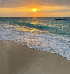 a sunset on the beach with a boat in the water at Coco Cabaña Barú in Cartagena de Indias +11 photos