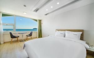 ein Schlafzimmer mit einem großen Bett und einem Tisch mit Stühlen in der Unterkunft VIEW Hotel Geoje in Geoje