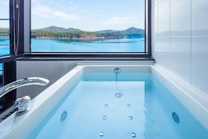 a bath tub with a window with a view of the water at Yeosu K-Park Spa Pension in Yeosu