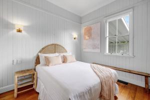 a bedroom with a bed with white sheets and a window at Paddy's Place in Bangalow +17 photos