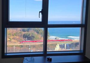 a window with a view of a train through it at Donghae Eoul Stay in Donghae