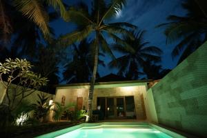 a villa with a swimming pool at night at Senang Private Villa in Gili Trawangan