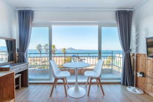 a living room with a table and chairs and a balcony at Udo Daol Pension in Jeju