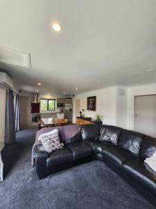 a black leather couch in a living room at Mill Road Retreat Ohaupo in Kaipaki