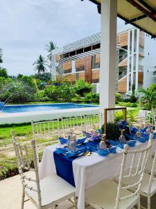 a table with blue napkins and chairs next to a pool at Alzurich Private Resort in Dauin