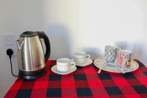 a tea kettle and three cups and saucers on a table at Samee Home in Midigama East