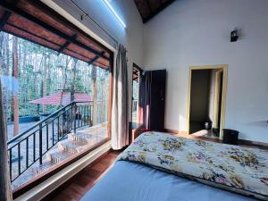 a bedroom with a bed and a large window with a balcony at janani ecostay in Chikmagalūr