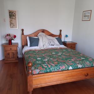 a bedroom with a wooden bed with a green comforter at Little Blue Bach in Whanganui