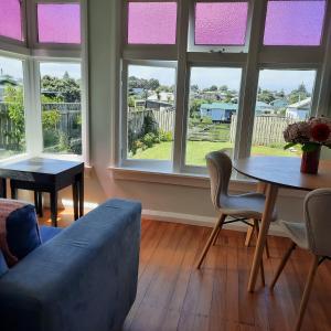 a living room with a couch and a table and windows at Little Blue Bach in Whanganui