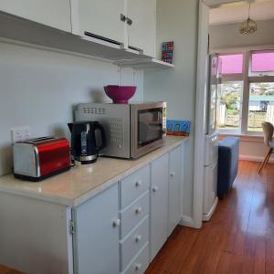 a kitchen with a counter with a microwave and appliances at Little Blue Bach in Whanganui