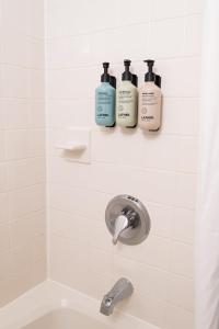 a bathroom with three shampoo bottles on the wall at Brass Lantern Inn in Stowe +181 photos