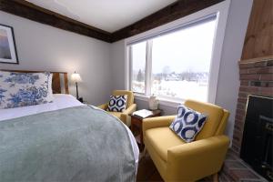 a bedroom with a bed and two chairs and a fireplace at Brass Lantern Inn in Stowe
