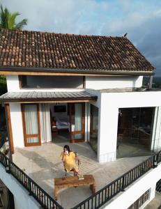 a woman sitting on a bench in front of a house at SereneVbes - Kandy in Kandy