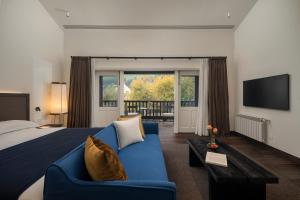a hotel room with a blue couch and a television at Mocun Resort in Deqing