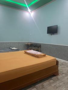 a bedroom with a bed with a tv on the wall at Khách sạn Vườn Bưởi in Ấp Bình Sơn