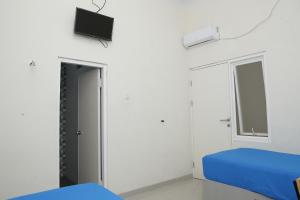 a bedroom with a bed and a tv on the wall at linns house borobudur syariah malang in Blimbing