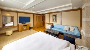 a bedroom with a blue couch and a television at Hotel Crespa in Shizuoka