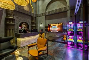 Eine Bar mit einem gelben Stuhl in einem Raum mit violettem Licht in der Unterkunft Pynt Hotel 8 in Ho-Chi-Minh-Stadt