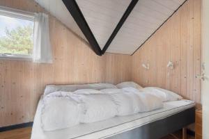 a bed in a room with a wooden wall at 2555-Romo-A-M-Listsvej-6 in Høm