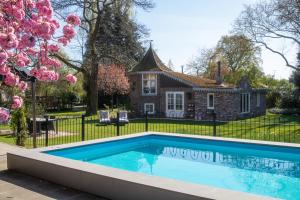 a swimming pool in front of a house at Petit Château luxe vakantiehuis, prive hottub en zwembad in Heythuysen