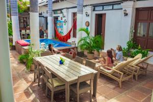 a group of children sitting on a patio with a table and a pool at Villana's Hostal Santa Marta in Santa Marta