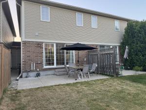 a patio with a table and an umbrella in front of a house at Gorgeous 3-Bedroom 3Bathroom house in Kitchener